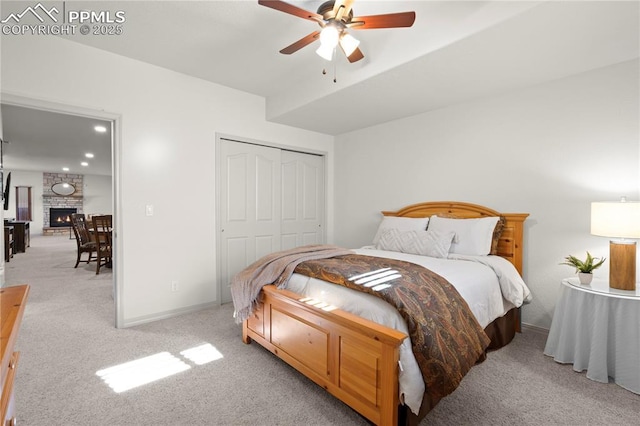 carpeted bedroom featuring ceiling fan, a closet, and a fireplace