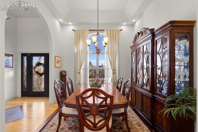 dining room featuring light hardwood / wood-style flooring, a towering ceiling, and an inviting chandelier