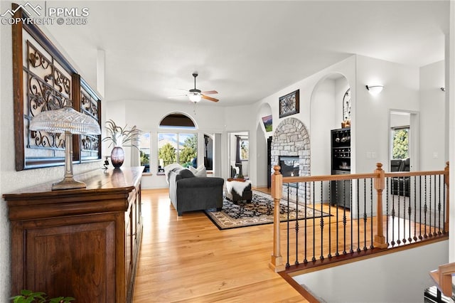 living room with ceiling fan, light hardwood / wood-style floors, and a fireplace