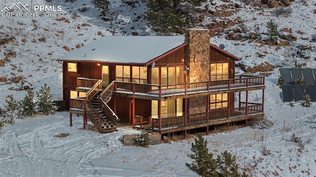 snow covered rear of property featuring a wooden deck