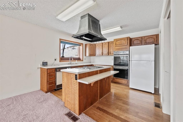 kitchen featuring a textured ceiling, island range hood, white appliances, and a center island