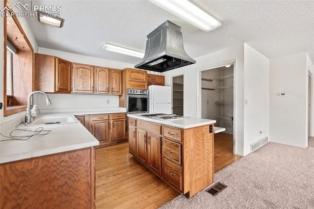 kitchen featuring sink, white appliances, a textured ceiling, a kitchen island, and island range hood