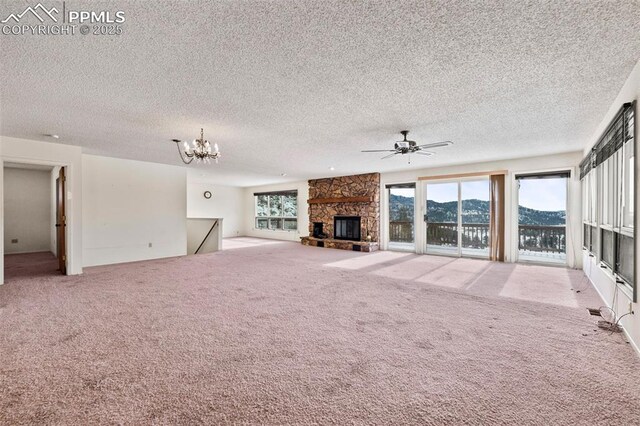 unfurnished living room featuring a textured ceiling, a mountain view, light colored carpet, and a stone fireplace