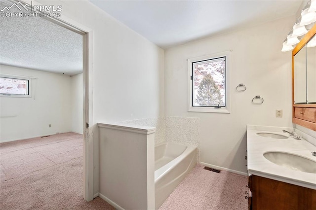 bathroom with vanity, a wealth of natural light, a tub, and a textured ceiling