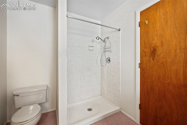 bathroom with a tile shower and toilet