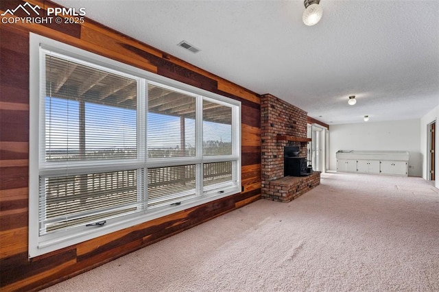 unfurnished living room featuring carpet floors, a textured ceiling, and wood walls