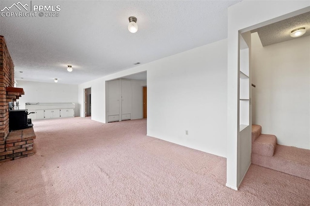 unfurnished living room featuring light colored carpet, a textured ceiling, and a fireplace