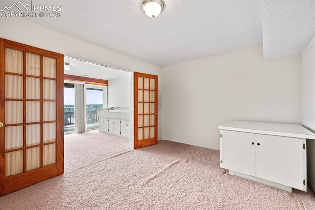 carpeted spare room with a textured ceiling and french doors