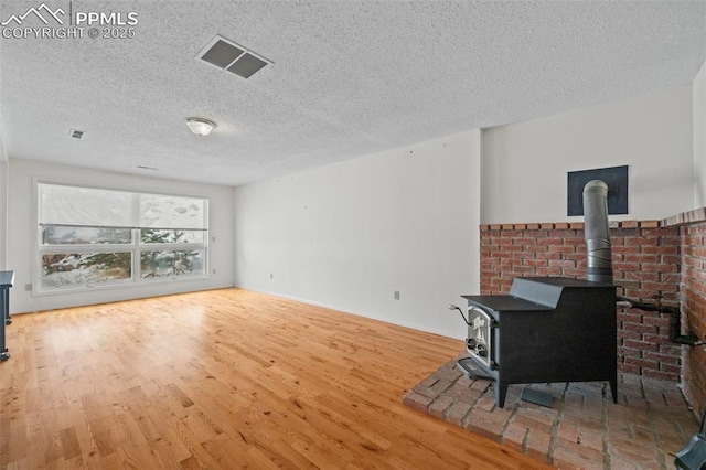 living room featuring light hardwood / wood-style floors, a wood stove, and a textured ceiling