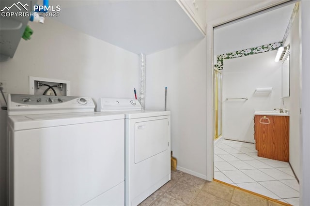 clothes washing area with sink, washing machine and clothes dryer, and light tile patterned floors