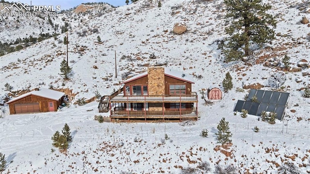 snow covered property featuring a mountain view, a garage, and an outdoor structure