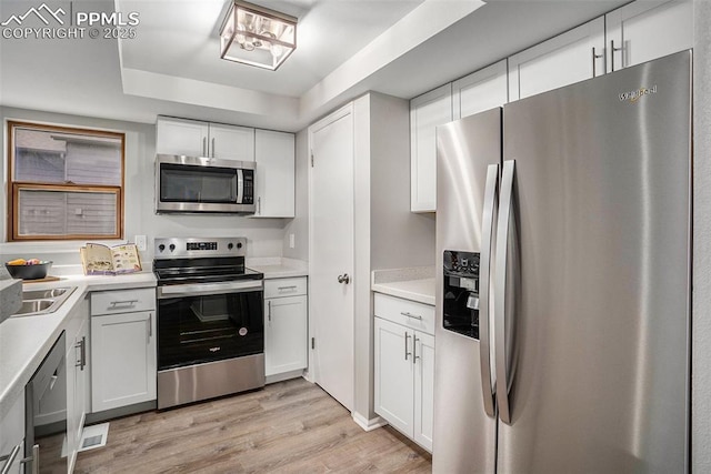 kitchen with light wood-type flooring, white cabinetry, and appliances with stainless steel finishes