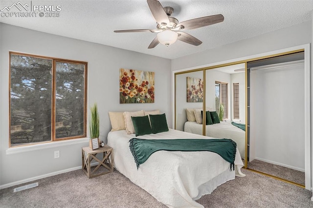 carpeted bedroom with ceiling fan, a textured ceiling, and a closet