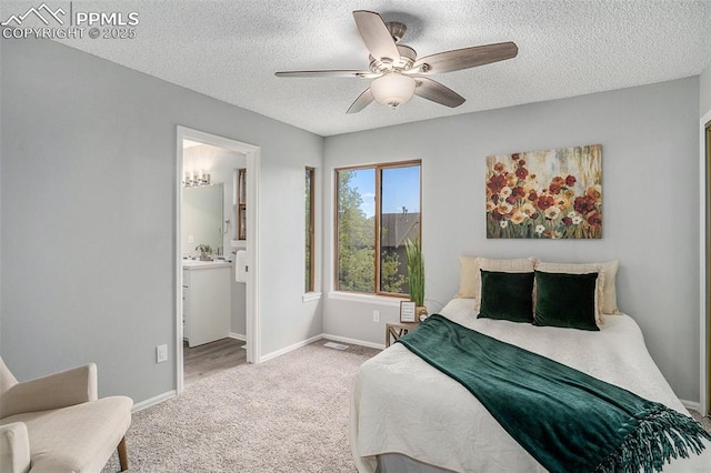 carpeted bedroom featuring ceiling fan, a textured ceiling, and ensuite bath