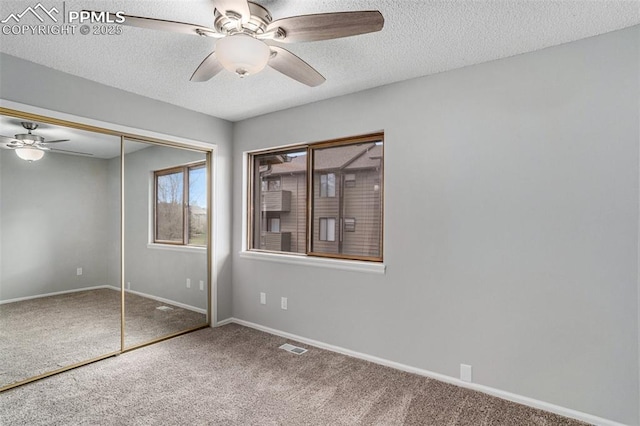 unfurnished bedroom featuring ceiling fan, a textured ceiling, a closet, and carpet floors