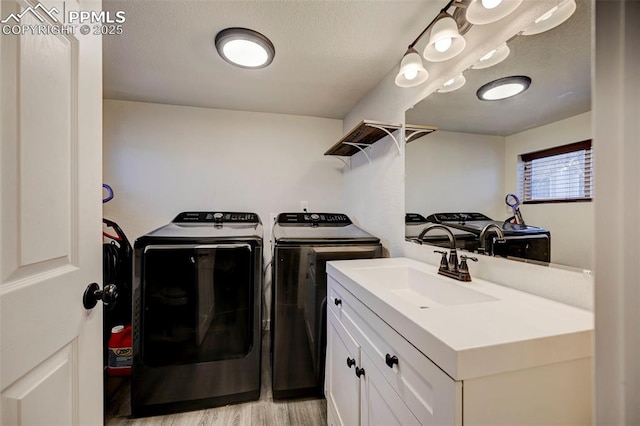 clothes washing area featuring washer and dryer, sink, and light hardwood / wood-style flooring