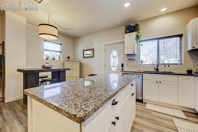 kitchen featuring dishwasher, a kitchen island, pendant lighting, white cabinets, and sink