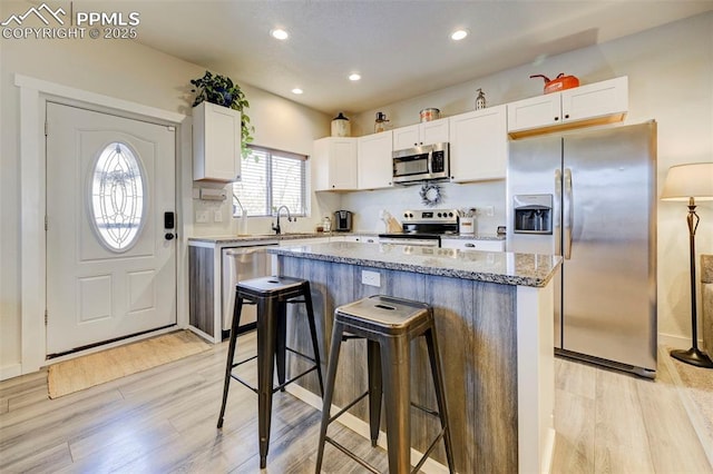 kitchen featuring white cabinetry, a breakfast bar area, stainless steel appliances, a center island, and sink