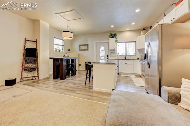 kitchen featuring decorative light fixtures, a center island, a breakfast bar, white cabinetry, and stainless steel appliances