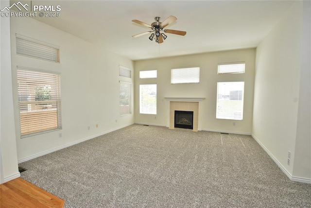 unfurnished living room featuring light carpet, ceiling fan, and a wealth of natural light