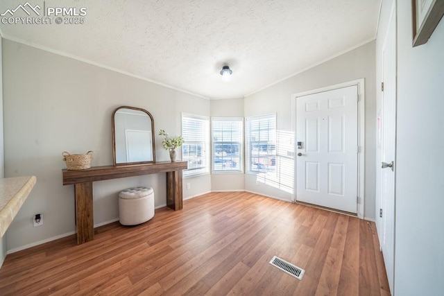 entryway featuring a textured ceiling, light hardwood / wood-style flooring, and crown molding