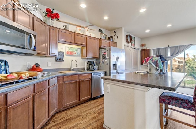 kitchen with sink, a center island, a kitchen breakfast bar, light hardwood / wood-style flooring, and appliances with stainless steel finishes