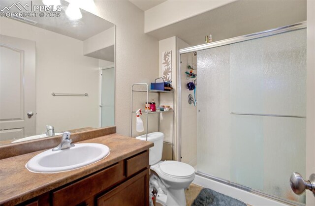 bathroom featuring an enclosed shower, vanity, and toilet