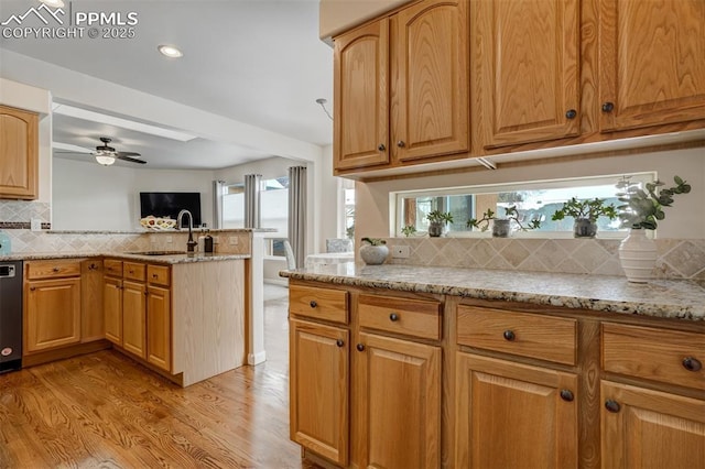 kitchen featuring sink, light hardwood / wood-style flooring, kitchen peninsula, and light stone counters