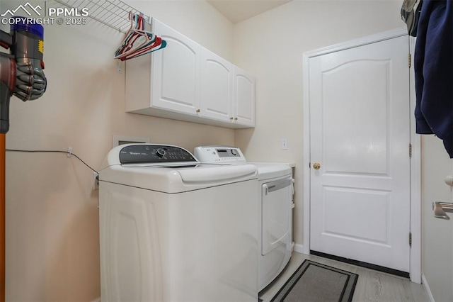 clothes washing area featuring cabinets, washing machine and dryer, and light wood-type flooring