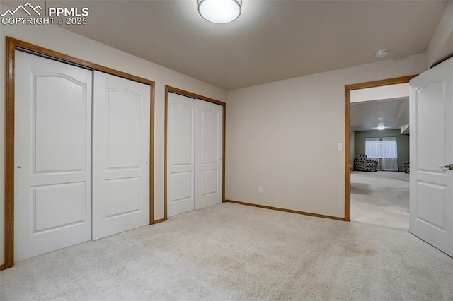 unfurnished bedroom with two closets and light carpet