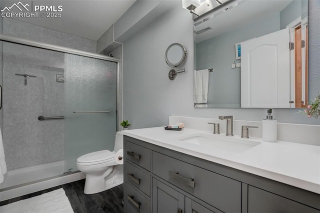 bathroom with vanity, toilet, a shower with door, and hardwood / wood-style flooring