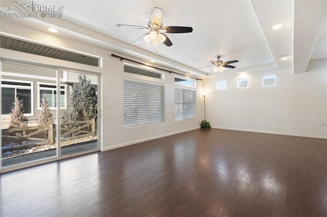 spare room featuring dark wood-type flooring, ceiling fan, and a raised ceiling