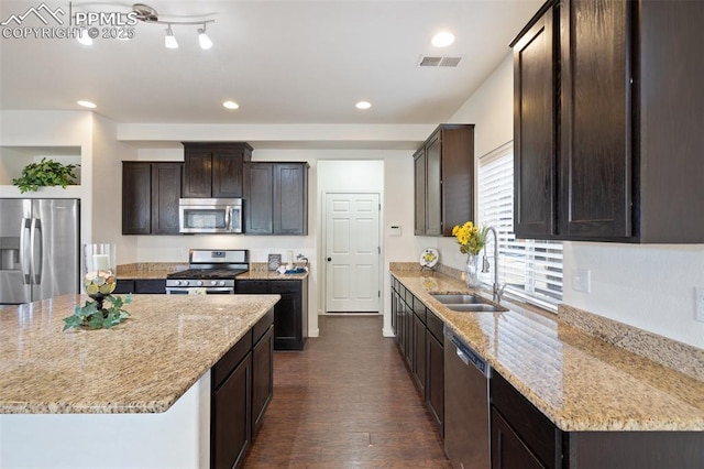 kitchen featuring a kitchen island, sink, dark brown cabinetry, light stone countertops, and stainless steel appliances