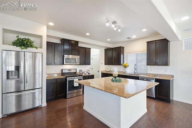 kitchen featuring dark brown cabinetry, a kitchen island, dark wood-type flooring, stainless steel appliances, and sink