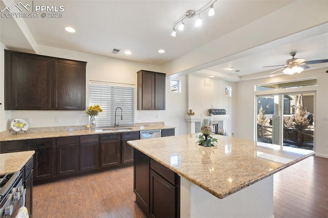 kitchen with light hardwood / wood-style floors, appliances with stainless steel finishes, dark brown cabinets, a kitchen island, and sink