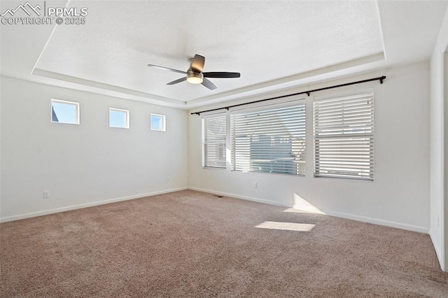 carpeted spare room featuring ceiling fan and a raised ceiling