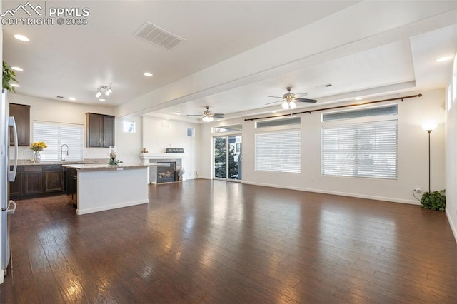 kitchen with ceiling fan, dark hardwood / wood-style floors, a center island, sink, and dark brown cabinetry