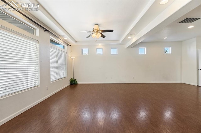 unfurnished room featuring ceiling fan, dark hardwood / wood-style floors, and a tray ceiling