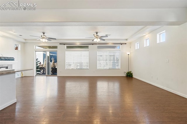 unfurnished living room featuring dark wood-type flooring, plenty of natural light, and a raised ceiling