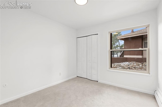 unfurnished bedroom featuring a closet, a baseboard radiator, and light carpet