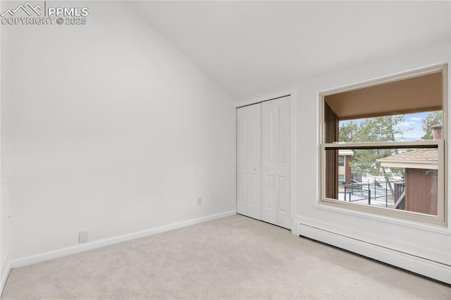 unfurnished bedroom with lofted ceiling, light colored carpet, a baseboard radiator, and a closet