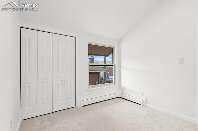 unfurnished bedroom featuring vaulted ceiling, a baseboard heating unit, light colored carpet, and a closet