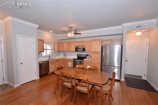 kitchen featuring hardwood / wood-style flooring, stainless steel appliances, ornamental molding, ceiling fan, and sink