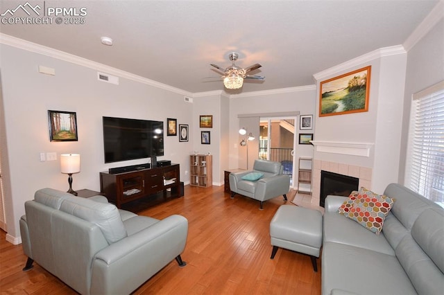 living room featuring a fireplace, ceiling fan, crown molding, and hardwood / wood-style floors