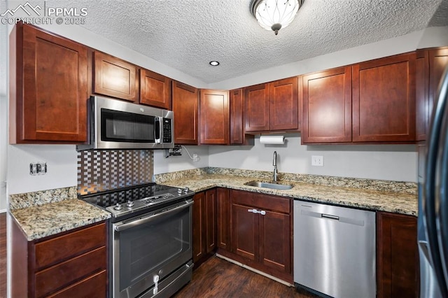 kitchen with appliances with stainless steel finishes, light stone counters, a textured ceiling, and sink