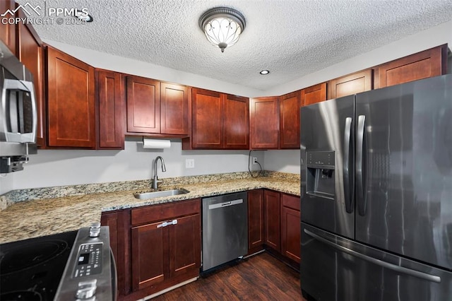 kitchen featuring stainless steel appliances, sink, a textured ceiling, light stone countertops, and dark hardwood / wood-style flooring