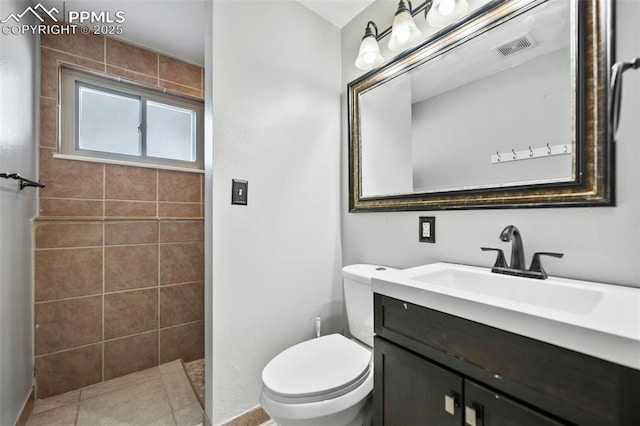 bathroom featuring tile patterned floors, a tile shower, vanity, and toilet