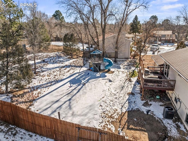 snowy yard with a deck and a playground