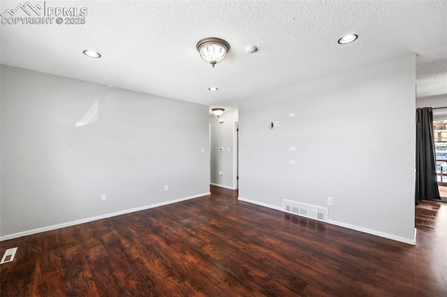 empty room with a textured ceiling and dark hardwood / wood-style flooring