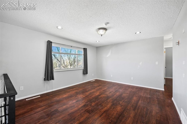 unfurnished room with a textured ceiling and dark hardwood / wood-style floors